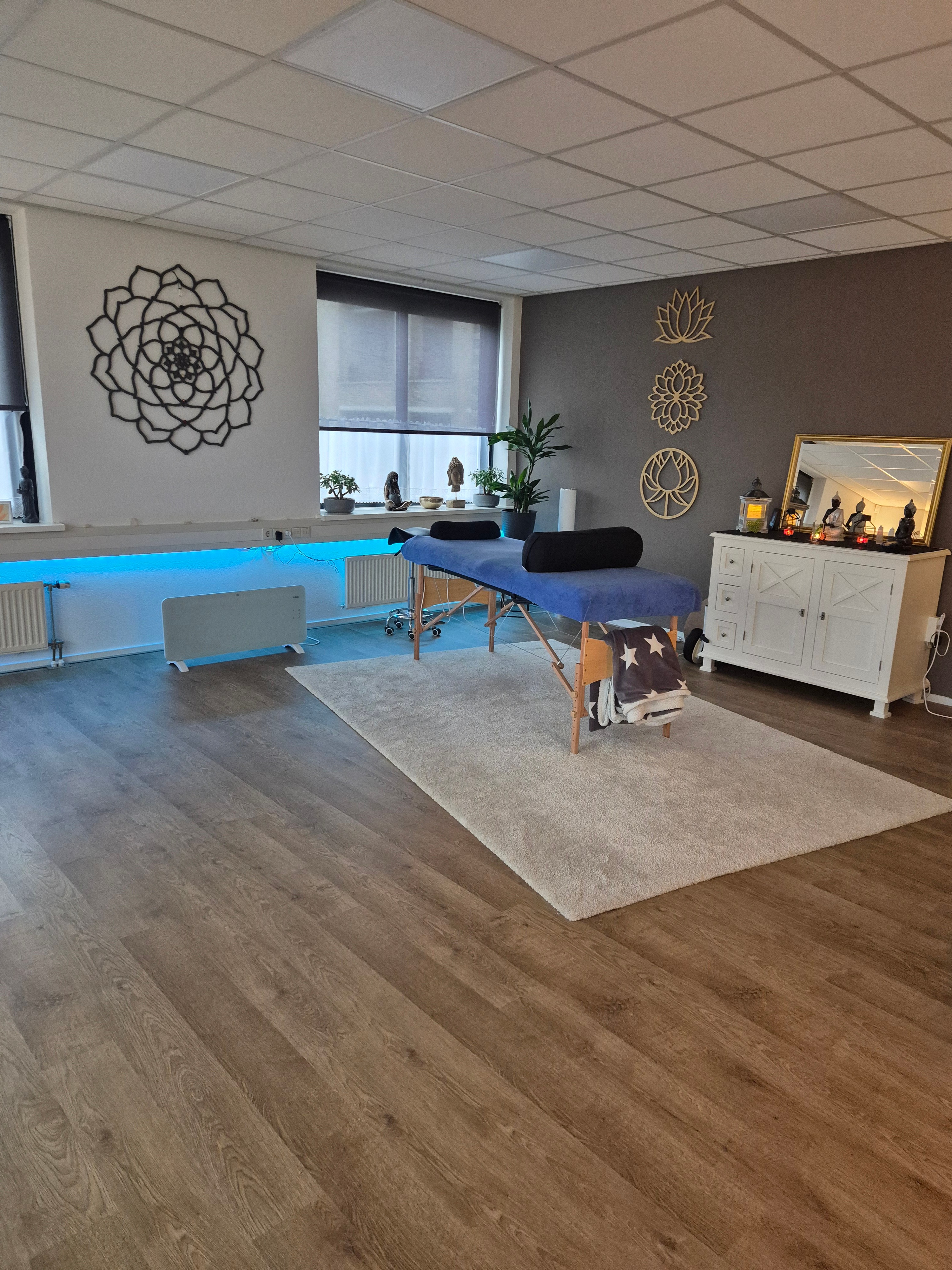 Behandelruimte Essence Healing - sfeervolle ruimte met behandeltafel, lotus wanddecoratie en Boeddha beelden